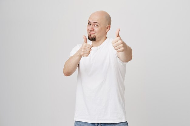 Bald handsome guy smiling, showing thumbs-up in approval
