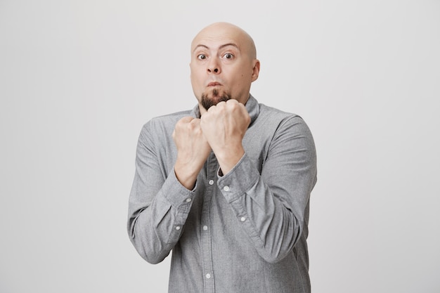 Bald man fighting, raise clenched fists in boxing pose