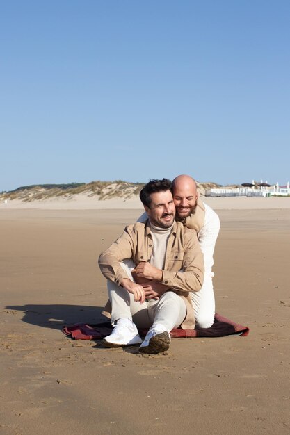 Bald man hugging boyfriend on beach