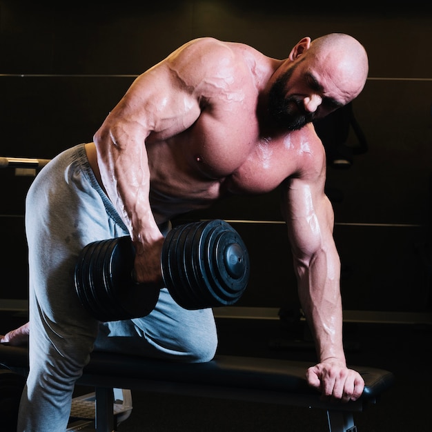 Bald man lifting heavy dumbbell