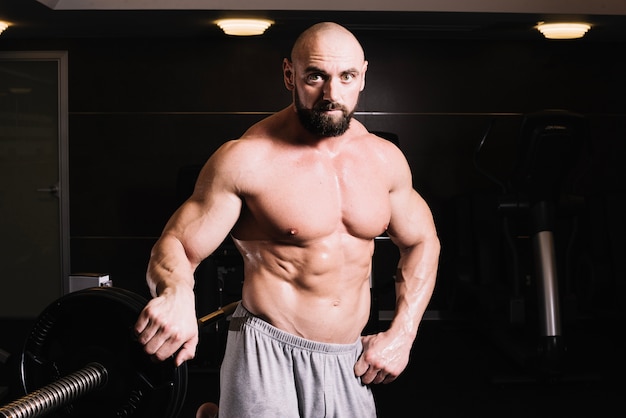 Free photo bald man posing near barbell