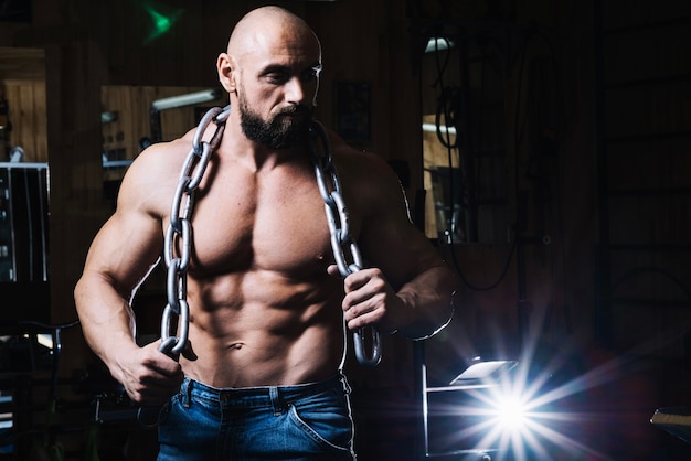 Bald muscular man holding chain