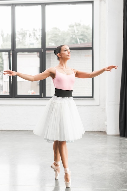 Free photo ballerina dancer dancing on tip toe in dance floor