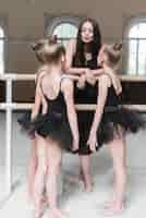 Free photo ballerina girls looking at female trainer pouting near the barre