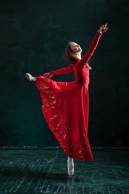 Free photo ballerina posing in pointe shoes at black wooden pavilion