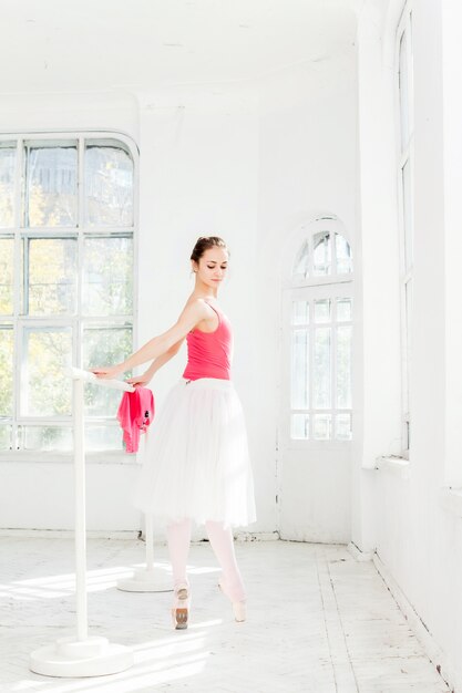 Ballerina posing in pointe shoes at white wooden pavilion