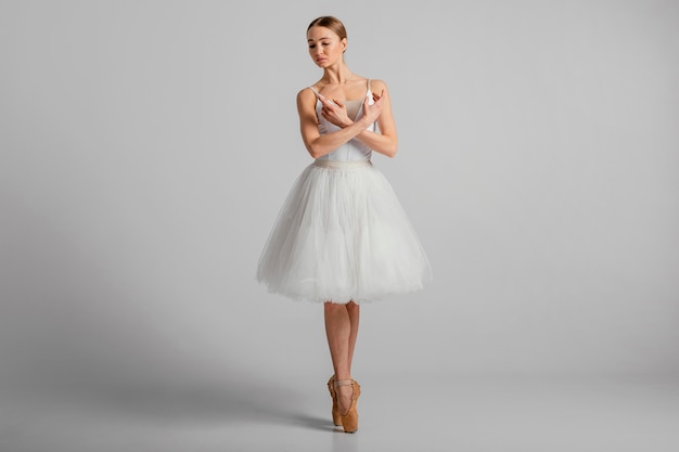 Free photo ballerina posing with pointe shoes full shot