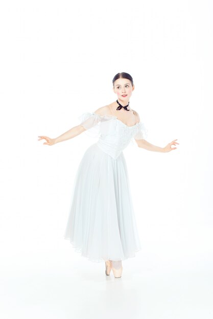 Ballerina in white dress posing on pointe shoes, studio white.