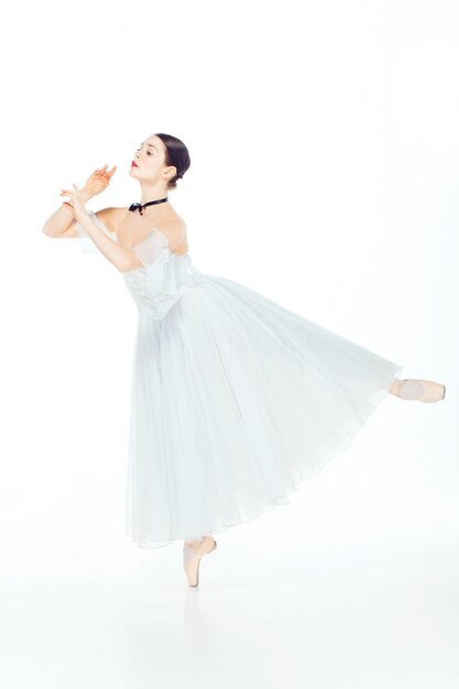 Ballerina in white dress posing on pointe shoes