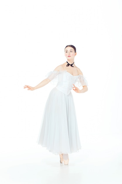 Балерина в белом платье позирует на пуанты