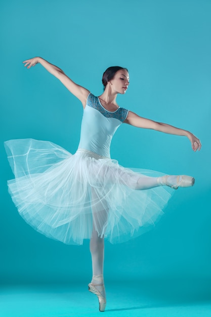 Балерина в белом платье позирует на пальцах ног