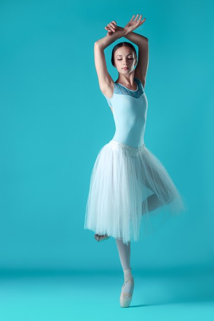 Балерина в белом платье позирует на пальцах ног