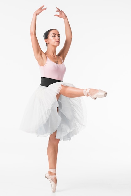 Ballerina in white tutu standing on tiptoe against white background