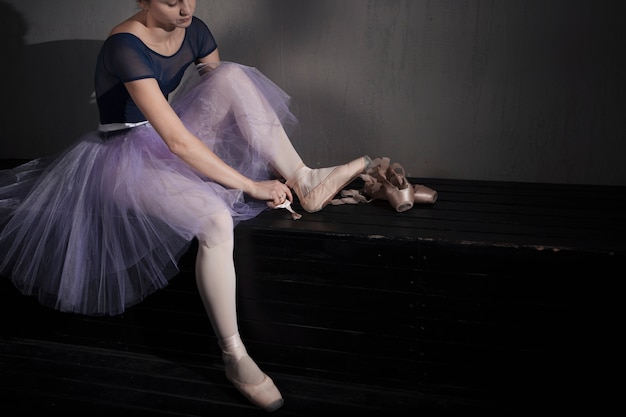 Ballet dancer putting on pointe shoes
