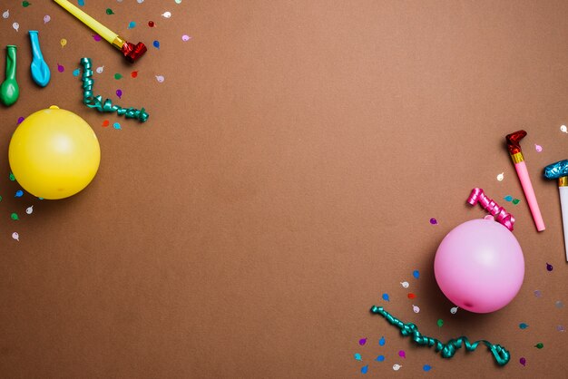 Balloons; confetti; streamers and party horn blower on the corner of the backdrop