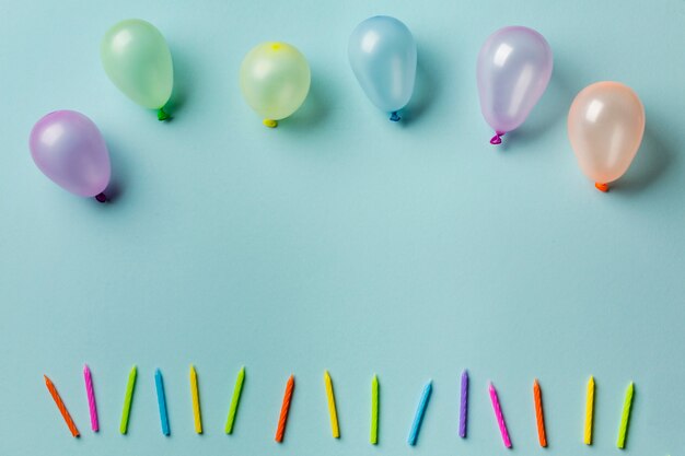 Balloons over the row of colorful candles against blue background