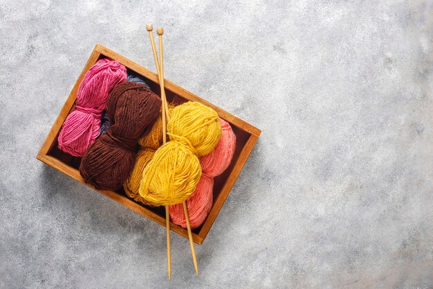 Balls of yarn in different colors with knitting needles.