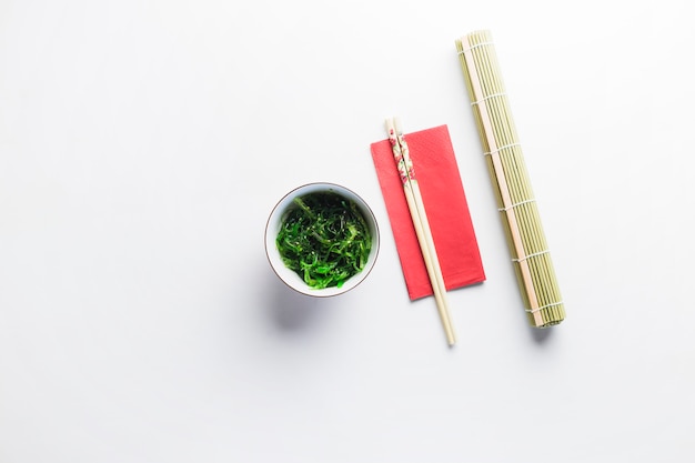 Free photo bamboo napkin near seaweed salad and chopsticks