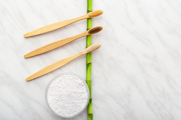 Bamboo toothbrush  bamboo plant dentifrice tooth powder on white marble background.flat lay copy space.biodegradable natural bamboo toothbrush.eco friendly zero waste dental care plastic free concept.