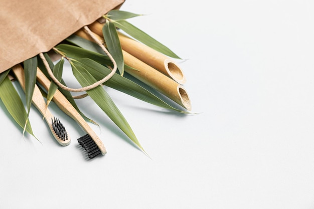 Free photo bamboo toothbrush and eco bag on a table with copy space on a white background styled composition of flat lay with bamboo leaves