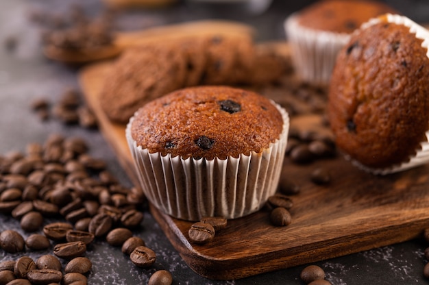 コーヒーの穀物が付いている木の皿に置かれるバナナのカップケーキ。