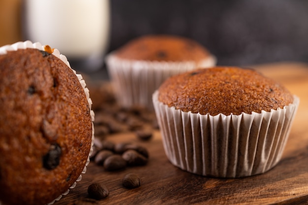 コーヒーの穀物が付いている木の皿に置かれるバナナのカップケーキ。