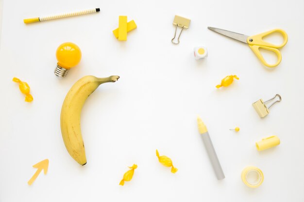 Banana, electric bulb, candies and stationeries on white background