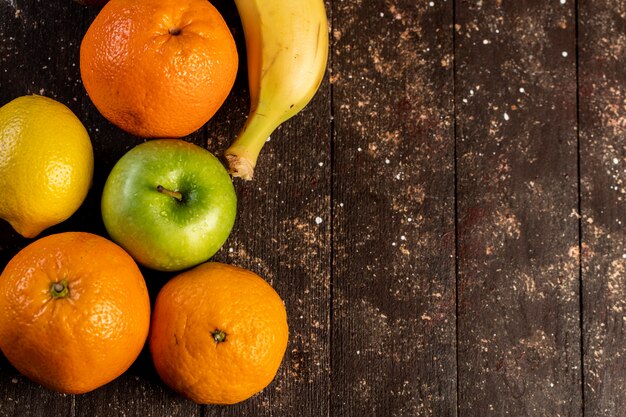 Banana lemon apple and mandarin on a wooden table