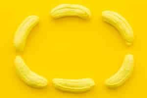 Free photo banana shaped candies forming frame on yellow background