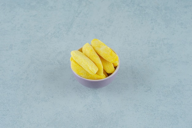 바나나 모양의 흰색 표면에 그릇에 씹는 사탕