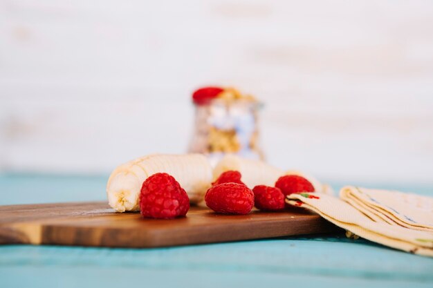 Banana slices and strawberries on wooden chopping board