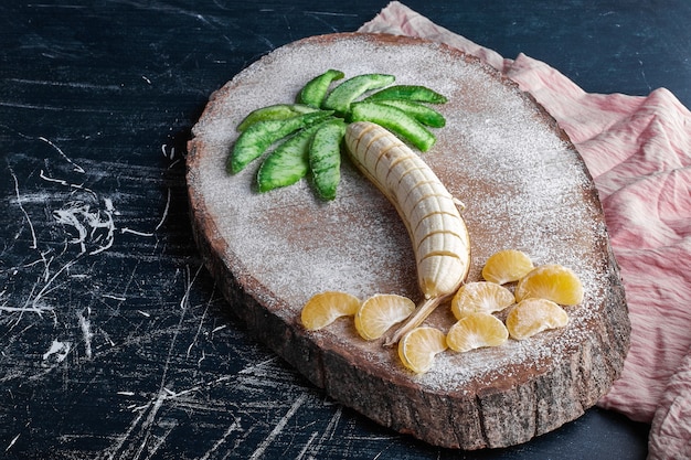 Banana with mandarines and dry avocado slices in palm tree shape. 