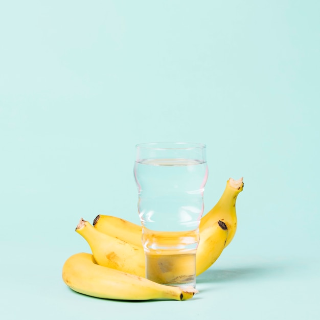 Bananas and glass of water copy space