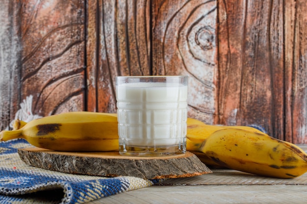 Foto gratuita banane con latte, vista laterale del tagliere sul tappeto in legno e kilim