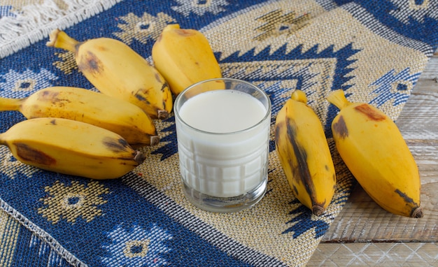 Banane con vista ad alto angolo di latte sul tappeto in legno e kilim