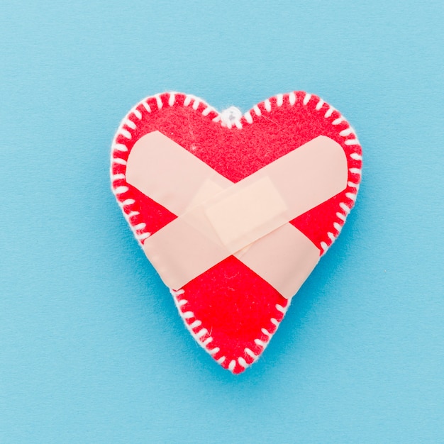 Bandage over the white stitch red heart shape on blue background