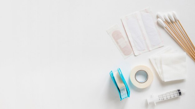 Bandages; cotton bud; sticking plaster; sterile gauze and syringe on white background