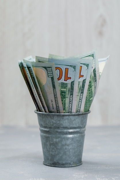 Free photo banknotes in mini bucket on plaster and wooden table .