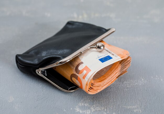 banknotes in purse on plaster table .