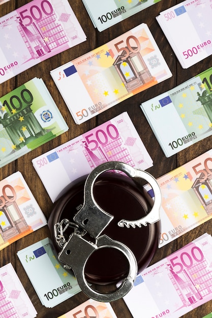 Banknotes on wooden table with handcuffs and stand