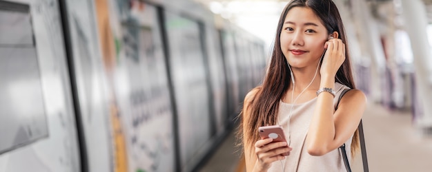젊은 아시아 여성 승객의 배너, 웹 페이지 또는 표지 템플릿 사용 및 음악 듣기 프리미엄 사진