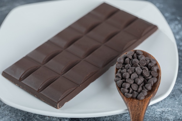 Плитка шоколада с шоколадной крошкой на мраморной поверхности.