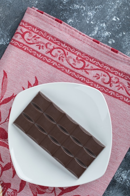 Bar of delicious chocolate on a white plate .