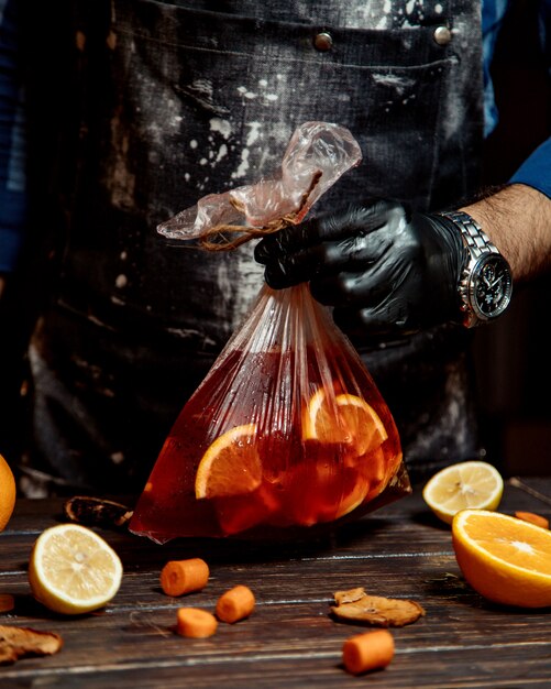 Bar tender holding a bag of cocktail with orange slices inside