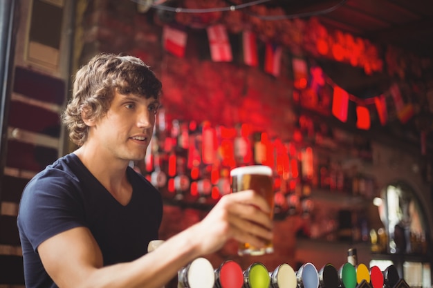 Bar tender offering glass of beer to customer