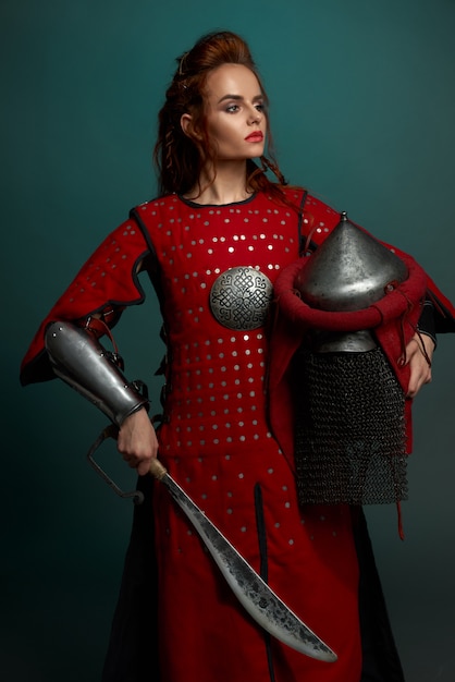 Free photo barbarian female fighter posing with helmet and knife