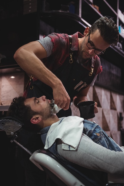 Free photo barber applying cream on clients beard