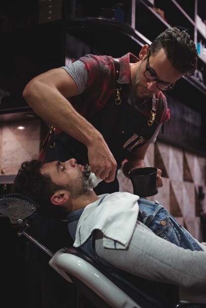 Barber applying cream on clients beard