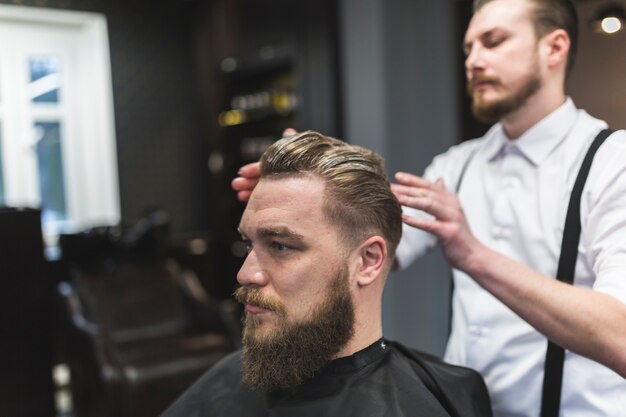 Barber applying mousse on hair of customer