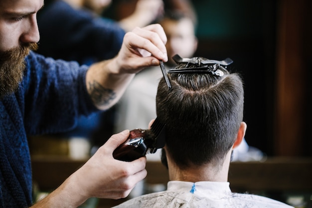 Free photo barber cuts man's hair with clipper and brush